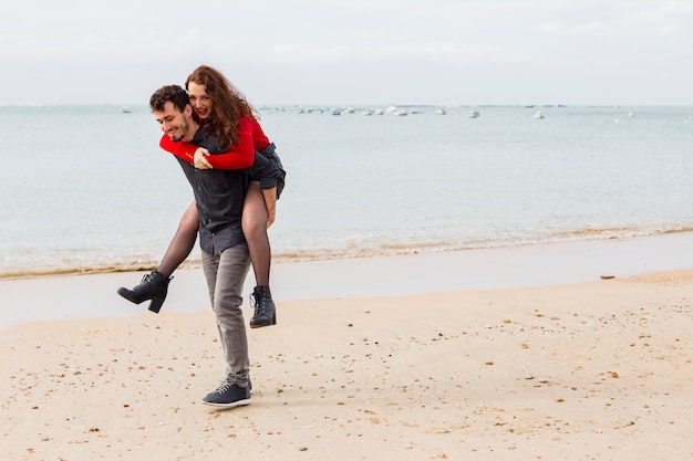 Free photo man holding woman on back on sea shore