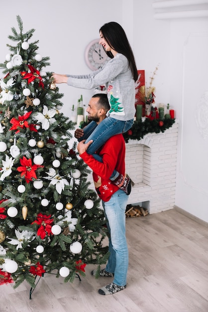 Man holding woman on neck near fir tree