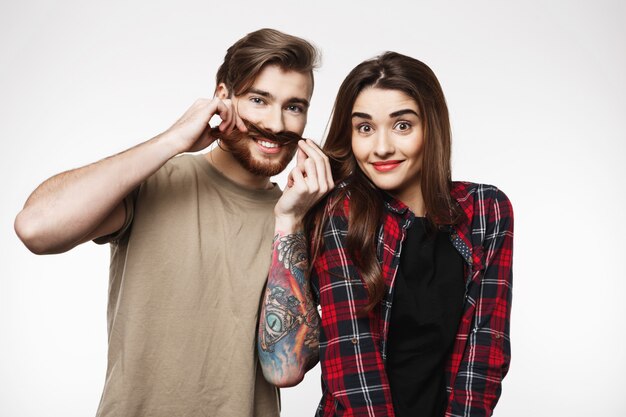 Man holding woman's hair as it is moustache, smiling happily.