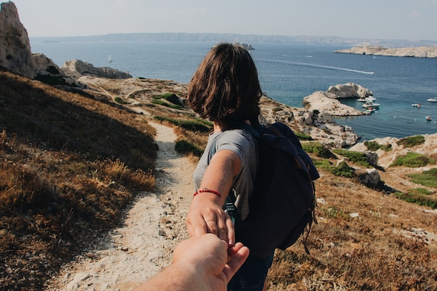 Man holding woman's hand near the sea during daytime