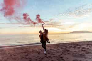 Free photo man holding woman with smoke bomb on back