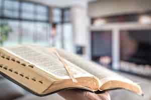 Foto gratuita un uomo tiene una bibbia contro il lato del soggiorno.