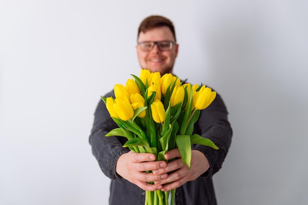 Man holds bouquet of yellow tulips in front of him. romantic gift for woman. white background