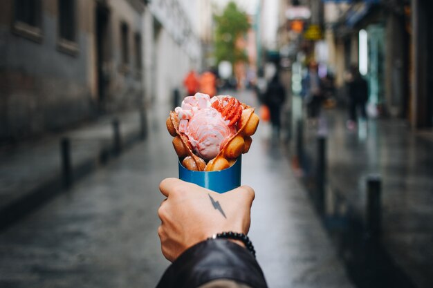 Free photo man holds bubble waffle from street food truck