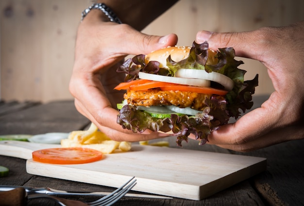 Man holds burger with hands and potato chip.