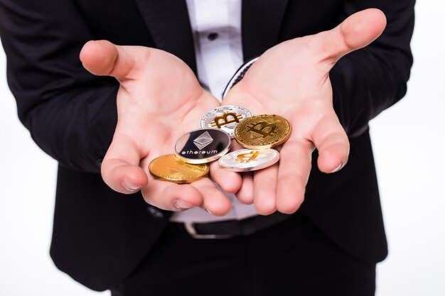 Мужчина держит в руках разные крипто-монеты на белом