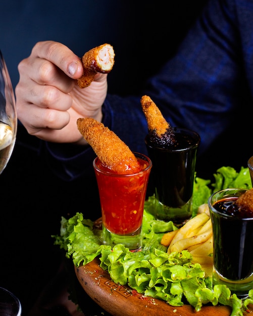 Man holds half-bitten fried shrimp served with sauce and fries