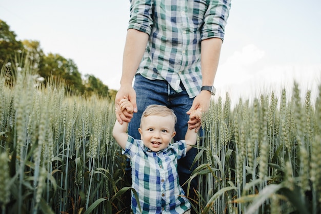 L'uomo tiene suo figlio per le mani tra il campo di grano