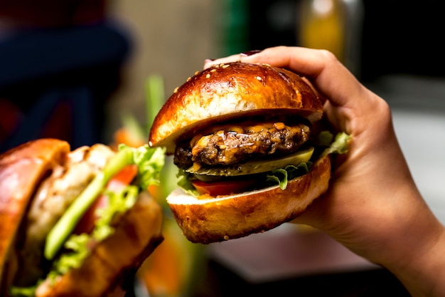 Man holds meat burger side view