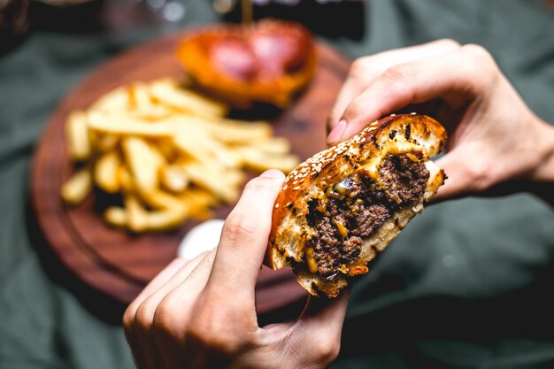 Man holds meat burger side view