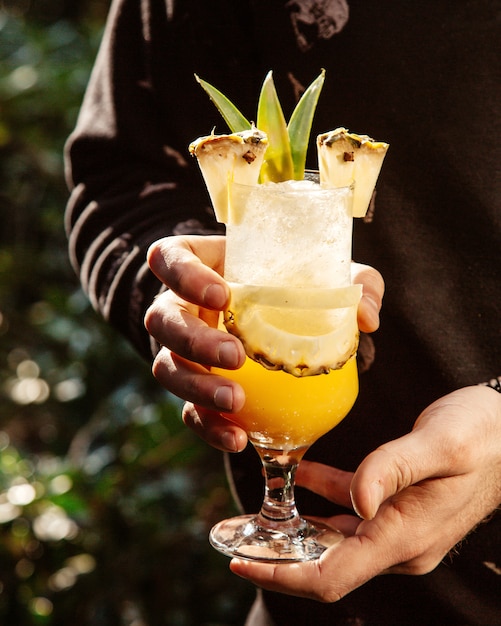 Free photo man holds pineapple juice with pineapple slice inside