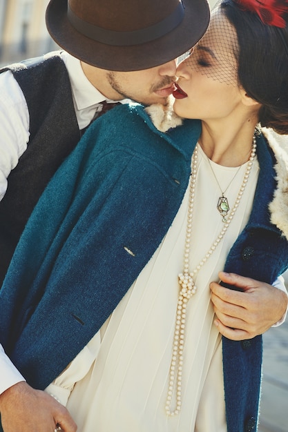 Man holds woman dressed in 30s style tender standing on the old street