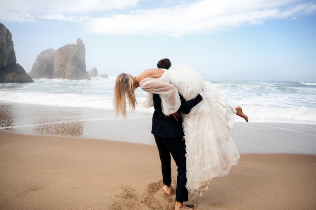 Foto gratuita l'uomo tiene la donna sulla sua spalla e sono sulla spiaggia dell'oceano
