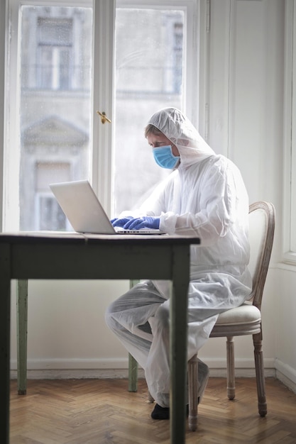 Free photo man at home during a video call in protective suit and mask