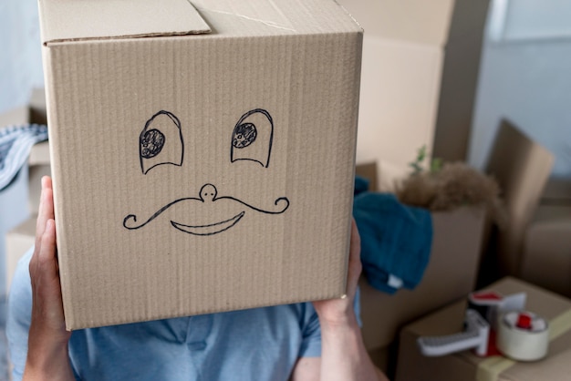 Free photo man at home on moving day acting silly with box over head