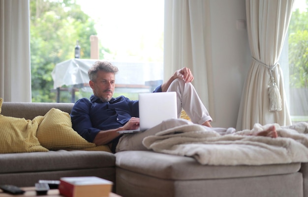 Man at home on the sofa uses a computer