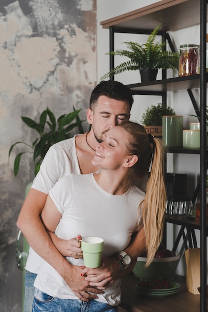 Man hugging her girlfriend holding cup of coffee