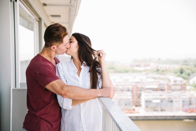 Man hugging and kissing woman on balcony