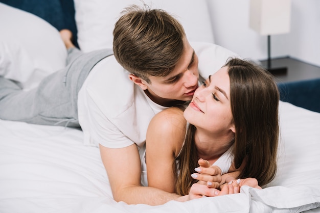 Man hugging woman from behind on bed 