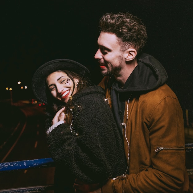 Free photo man hugging woman from behind in dark street