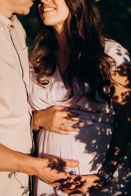 Man hugs beautiful pregnant woman tender standing before the lake 