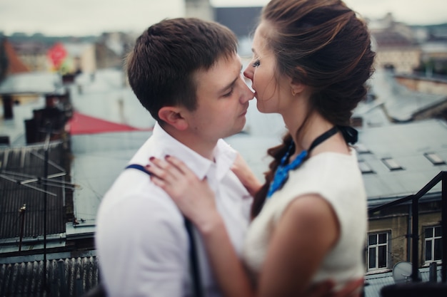 L'uomo abbraccia una bella donna graziosa e la bacia sul tetto