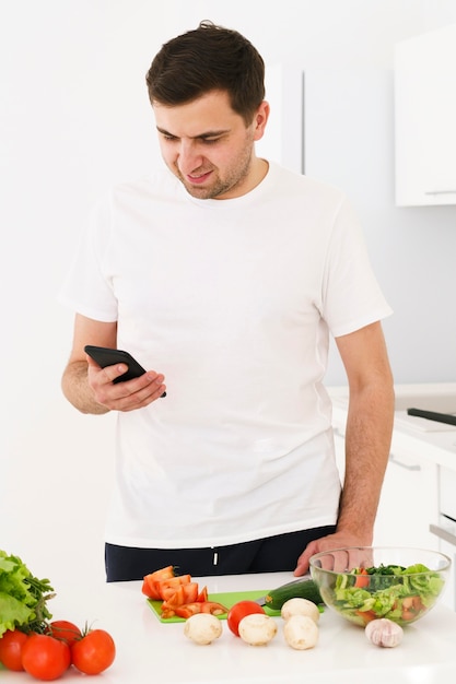 Бесплатное фото Человек на кухне с мобильным
