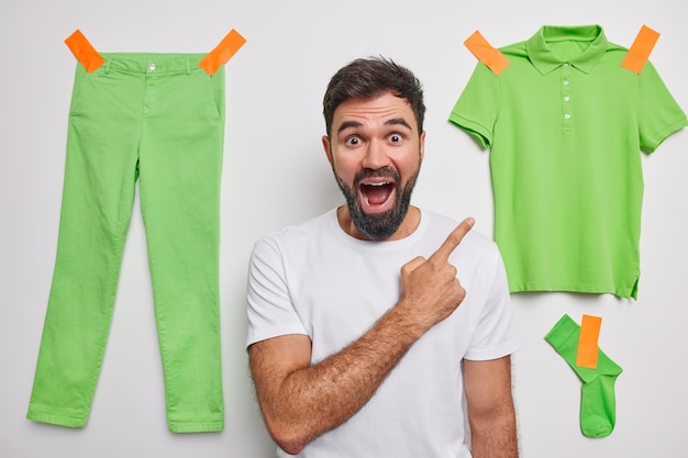  man indicates at clothing with glad expression attracts your attention to items for green clothes demonstrates something