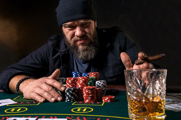 男はポーカーをしています。ゲームでの感情的な失敗、カードプレーヤーのゲームオーバー、愚かな選択に非常に怒っている男、銀行のすべてのチップを失います。勝利と敗北の概念