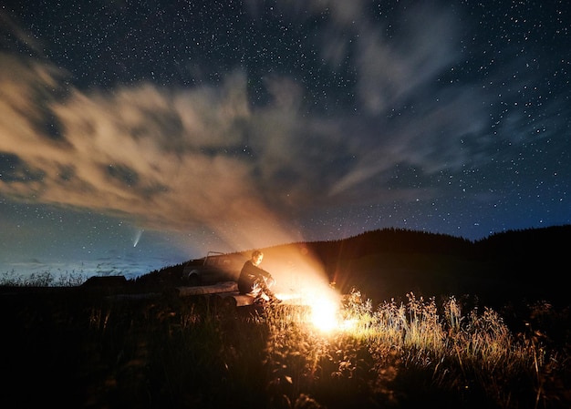 Free photo man is relaxing in mountains and lighting fire