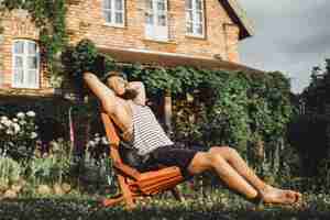 Free photo a man is resting in a country house. a bearded man enjoys the sunset on a green lawn.