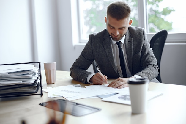 Man is sitting at the table. Guy in a business suit. Businessman  signs thedocuments