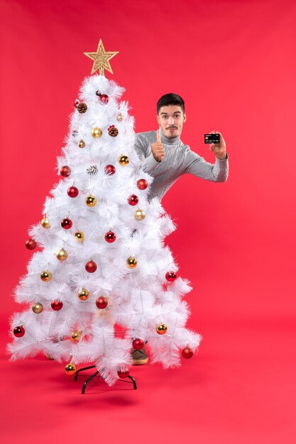 A man is standing next to the Christmas tree