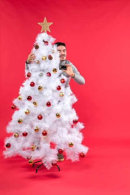 A man is standing next to the Christmas tree