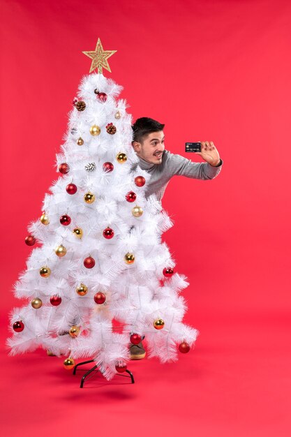 A man is standing next to the Christmas tree