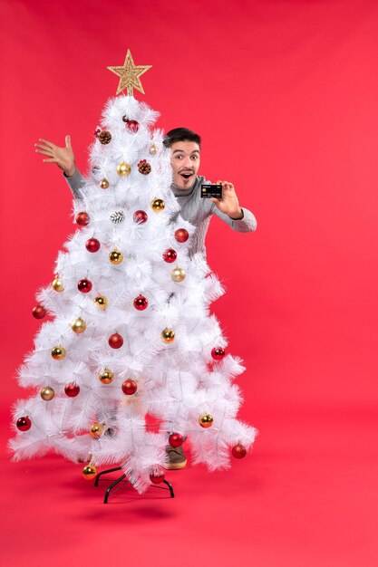 A man is standing next to the Christmas tree