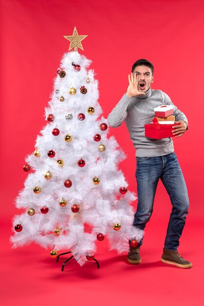 A man is standing next to the Christmas tree