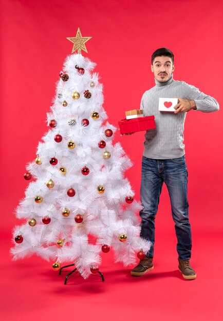 A man is standing next to the Christmas tree