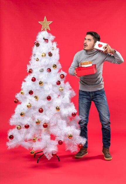 A man is standing next to the Christmas tree