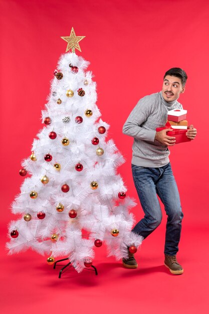 A man is standing next to the Christmas tree