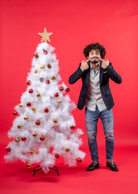 A man is standing next to the Christmas tree