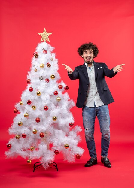 A man is standing next to the Christmas tree