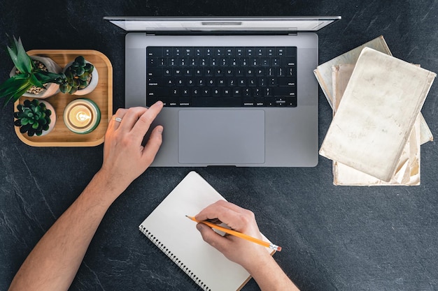 Un uomo sta utilizzando i libri di un laptop e la vista dall'alto di un notebook