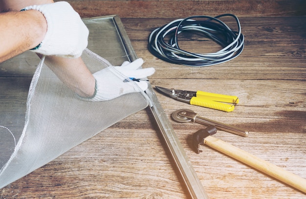 Man is working with mosquito wire screen installation