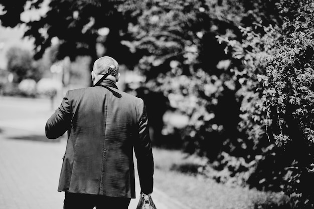 Man on jacket with cane skull head on shoulders and bag on hand Black and white