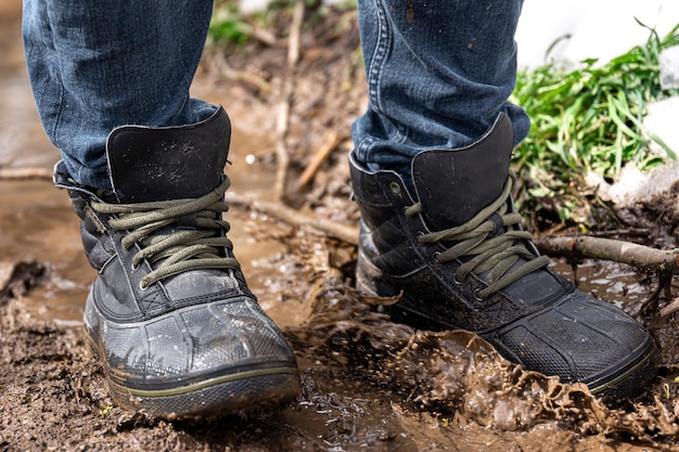 Foto gratuita un uomo in jeans e stivali cammina attraverso la palude in caso di pioggia