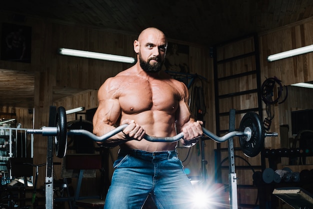 Foto gratuita uomo in jeans tenendo barbell