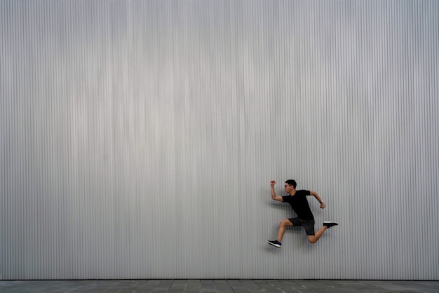 Un uomo che salta in aria su uno sfondo grigio con texture
