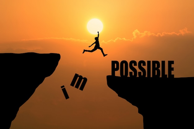 Человек прыгает над невозможным или возможно над утесом на фоне заката, концепция бизнес-концепции