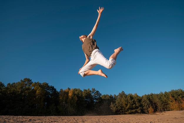 Человек прыгает на природе под низким углом